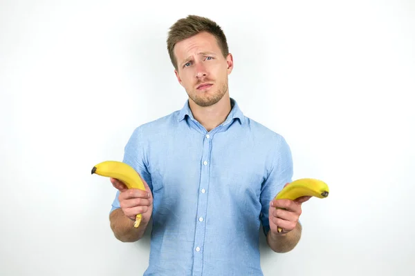 Jovem bonito homem segurando duas bananas frescas no isolado branco fundo — Fotografia de Stock
