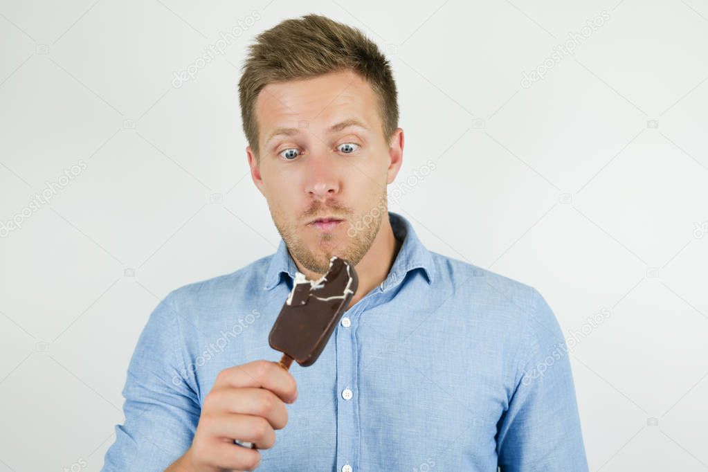 handsome young man just bit chololate ice-cream on isolated white background