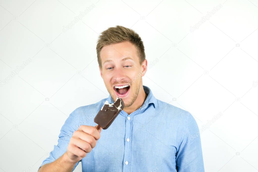 handsome young man is aboutto bite cold chololate ice-cream on isolated white background