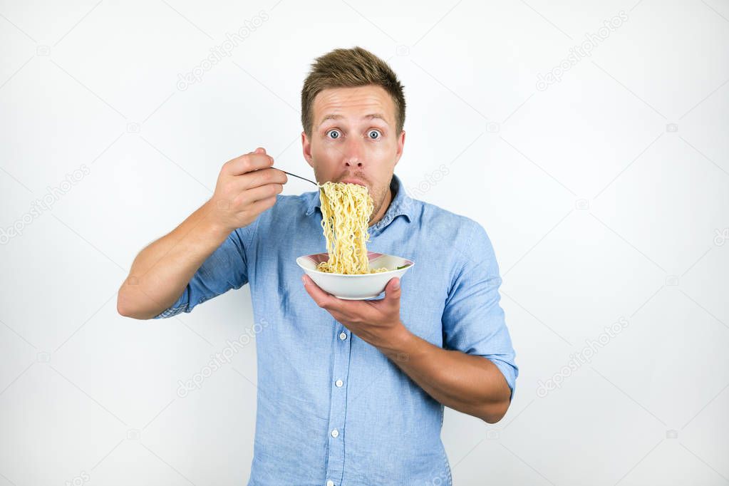 young handsome man eating hot noodles looking hungry on isolated white background