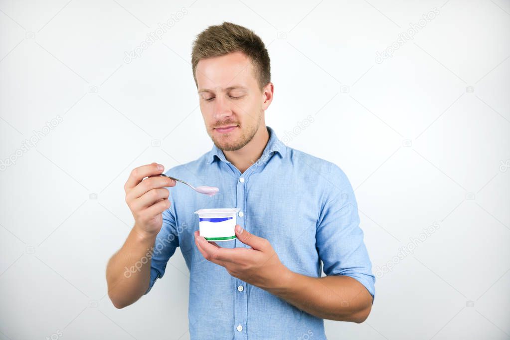 young handsome man eats yogurt with spoon on isolated white background