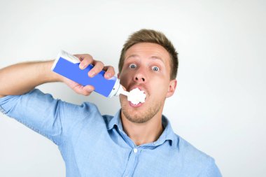 genç yakışıklı adam izole beyaz arka plan üzerinde sürpriz görünümlü doğrudan ağzına krem şanti spreyler