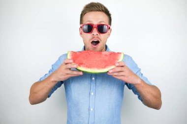 izole beyaz arka plan üzerinde karpuz ısırma kırmızı gözlük genç yakışıklı adam