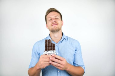 izole beyaz arka plan memnun görünümlü çikolata bar tutan genç yakışıklı adam