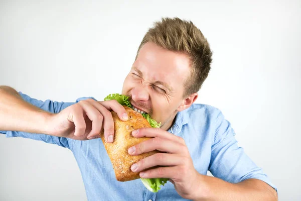 Joven guapo hombre mordiendo fresco sándwich con hambre en aislado blanco fondo —  Fotos de Stock