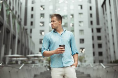 genç yakışıklı adam şehir merkezinde sokakta yürürken kahve fincan tutan