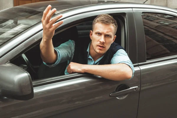 Jovem homem bonito sente raiva com outros motoristas sentados em seu carro — Fotografia de Stock