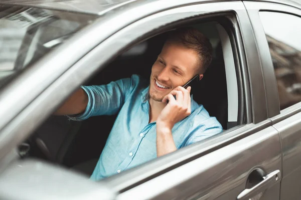 Giovane uomo bello guida in modo non sicuro avendo conversazione sul suo smartphone in fuga — Foto Stock