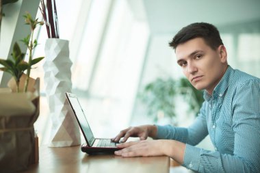 genç yakışıklı işadamı ofis yakınındaki kafede öğle yemeği beklerken onun laptop çalışır