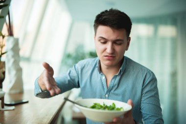 genç yakışıklı adam üzgün görünümlü garson gösteren salata memnun değil