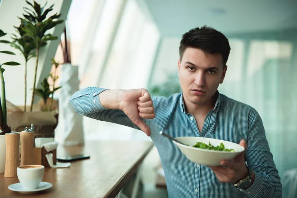 Jovem homem bonito não está satisfeito com a salada mostrando sinal de desgosto sentindo-se chateado — Fotografia de Stock