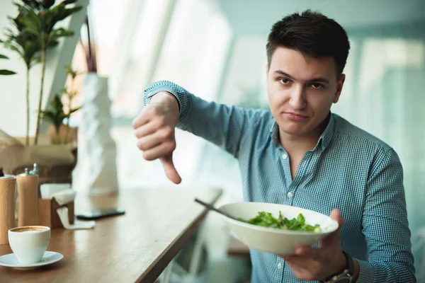 Jovem homem bonito não está satisfeito com a salada mostrando sinal de desgosto sentindo-se decepcionado — Fotografia de Stock