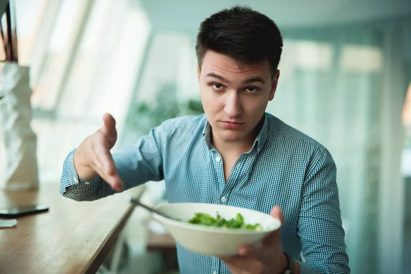 Ung stilig man är inte nöjd med sallad visar det till servitör — Stockfoto