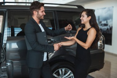yakışıklı adam yöneticisi yeni Suv el sıkışma yakınında duran bayilik merkezinde başarılı bir anlaşma sonra güzel esmer kadın müşteri araba anahtarları verir