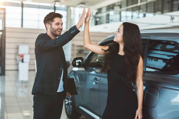 Przystojny człowiek kierownik i piękny brunetka kobieta klientka stojący w pobliżu nowy samochód po sukcesie Deal w dealerskiej Center — Zdjęcie stockowe