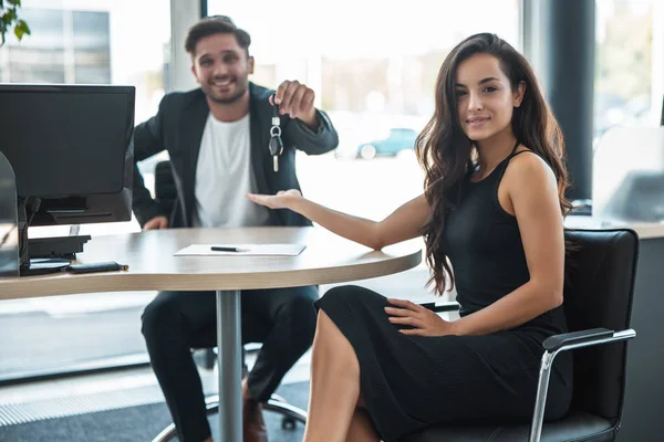 Tampan tersenyum manajer laki-laki memberikan kunci mobil setelah memegang kesepakatan sukses untuk klien wanita cantik di kantor dealer — Stok Foto