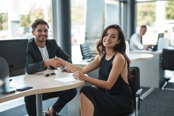 Tampan tersenyum manajer berjabat tangan dengan wanita cantik klien di kantor dealer setelah memegang kesepakatan sukses — Stok Foto