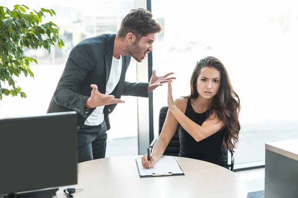 strict boss man swearing at employee woman for bad work at the office