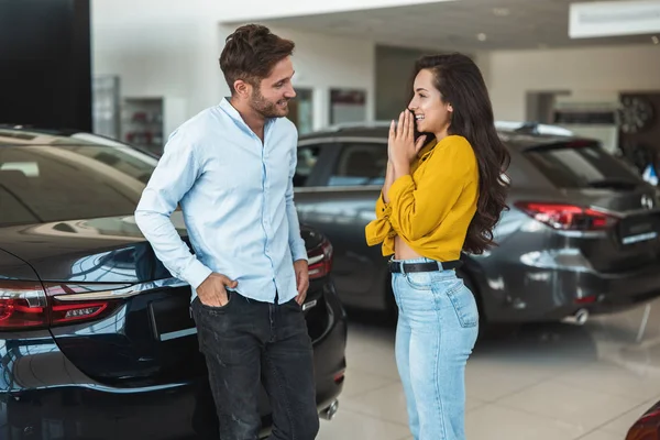 Hermosa pareja joven hombre y mujer elegir qué coche comprar en el centro de concesionarios — Foto de Stock