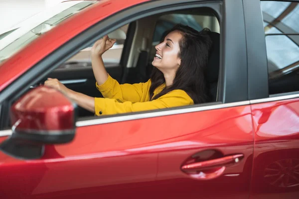 Bella donna bruna in cerca di nuova auto nel centro di concessionaria controllando l'interno — Foto Stock