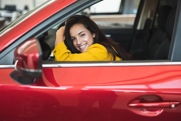 Bella donna bruna in cerca di nuova auto nel centro di concessionaria controllando l'interno del veicolo — Foto Stock