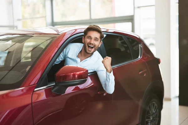 Młody przystojny mężczyzna szuka nowego samochodu w centrum dealerem wystające okna pojazdu — Zdjęcie stockowe