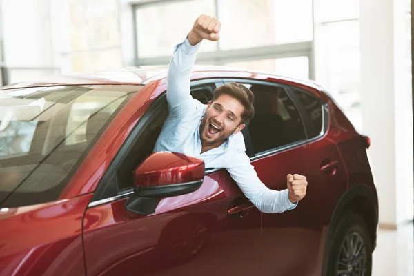 Młody przystojny mężczyzna szuka nowego samochodu w centrum dealerem wystaje okno pojazdu szczęśliwie — Zdjęcie stockowe