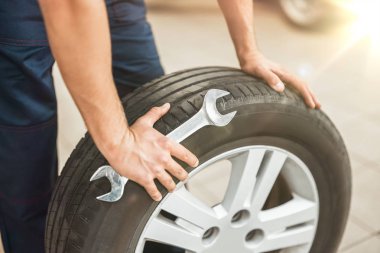 elinde lastik ve araba spanner tutan mekanik yakın