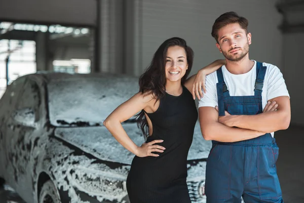 Jonge knappe man draagt uniforme en mooie vrouw klant staan in carwash station tevreden met uitstekende service — Stockfoto