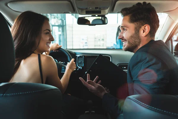 Bell'uomo e giovane bella donna controllare interni auto nuove, mentre la scelta di auto nuove nel centro di concessionaria — Foto Stock