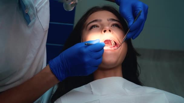 Fogorvos orvosi kesztyű és maszk gyógyítja a beteg fogak segítségével fogászati tükör és gát a találkozó során a fogászati klinikán - tömítés — Stock videók