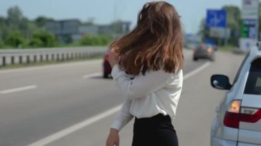 Güzel, genç, seksi esmer kadın arabasıyla sorun yaşadıktan sonra yoldan geçen arabaları durdurmaya çalışıyor.
