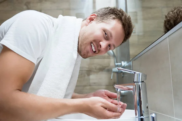 Mladý pohledný muž umývá si obličej v koupelně — Stock fotografie