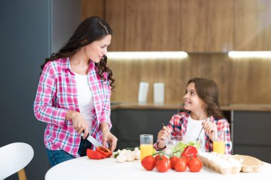 Genç, güzel bir kadın ve tatlı kızı mutfakta kahvaltı hazırlıyorlar.