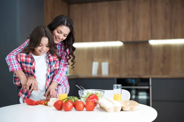 Schattig tiener dochter helpen haar mooi moeder naar koken ontbijt in de keuken op zoek gelukkig — Stockfoto