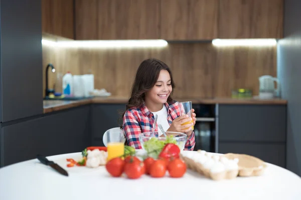 Söt tonåring dotter dricka apelsinjuice till frukost i köket ser glad ut — Stockfoto
