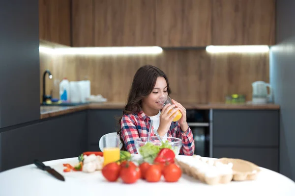 Schattig tiener dochter drinken oranje vers sap voor het ontbijt in de keuken op zoek gelukkig — Stockfoto