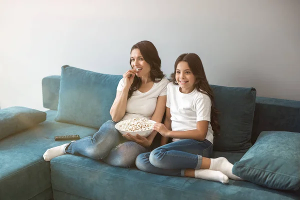 Belle jeune mère avec sa fille adolescente mignonne regarder dessin animé sur le canapé manger du pop-corn — Photo