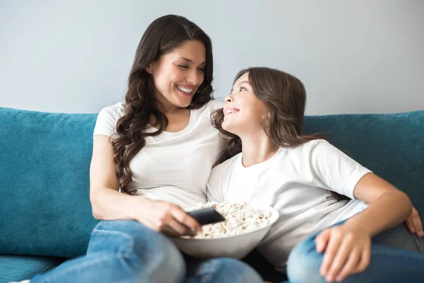 Belle jeune mère avec sa fille adolescente mignonne regarder un film sur le canapé manger du pop-corn se sentir à l'aise à la maison — Photo