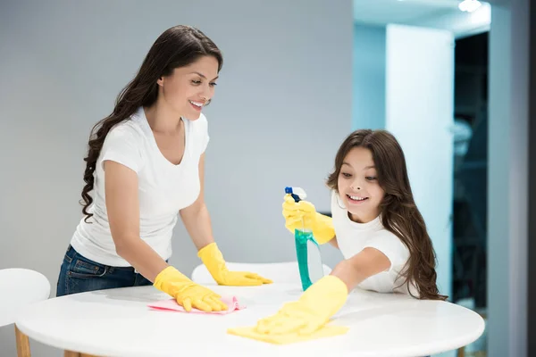Jeune belle femme et sa jolie fille adolescente en gants jaunes faire le nettoyage essuyant la poussière avec un chiffon — Photo