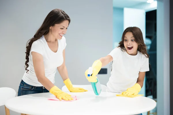 Joven hermosa mujer y su linda hija adolescente en guantes amarillos haciendo limpieza de limpiar el polvo con un trapo y detergente —  Fotos de Stock