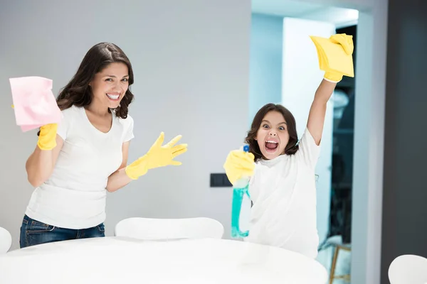 Young beautiful woman and her cute teen daughter holding rags in their hands feeling happy while cleaning the house — Stock Photo, Image