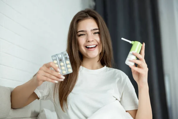 Young recovered after illness woman holding pills and medical spray looking happy — Stock Photo, Image