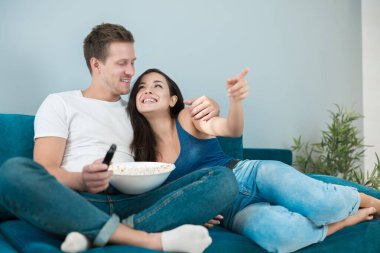 Genç çift, güzel esmer kadın ve kanepede film izleyen yakışıklı adam. Patlamış mısır yiyerek ona parmağını göstererek heyecan verici bir an yaşatıyor.