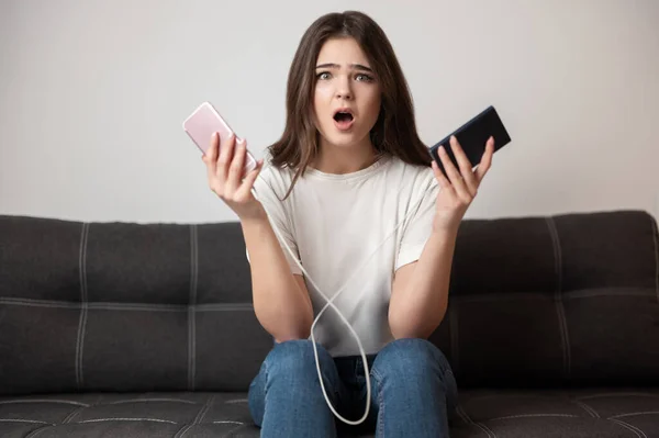 Brunette Woman Looks Surprised Holding Smartphone One Hand Portative Battery — Stock Photo, Image