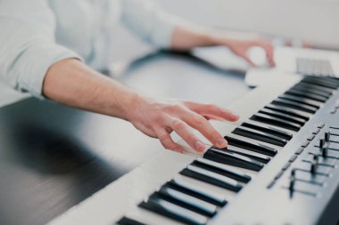 Genç adamın elleri klavye piyanosu çalıyor, müzik besteliyor, müzik kaseti çalıyor, sanat yapıyor..