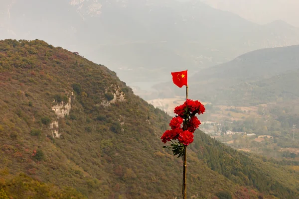 China flag and red flowers on a pole in the mountains — Stock Photo, Image