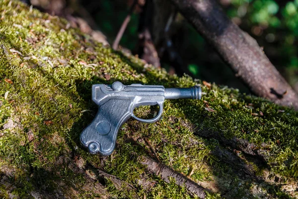Leksakspistol gjord av bly ligger på ett gammalt träd med mossa — Stockfoto