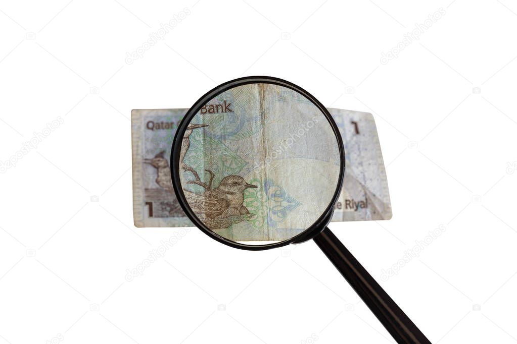 one Qatar Riyal bill and magnifying glass