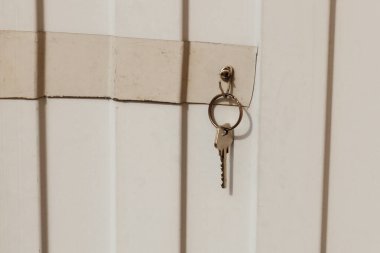 Anahtar metal bir çitteki kancaya asılı. Kapı kilidinin anahtarı..